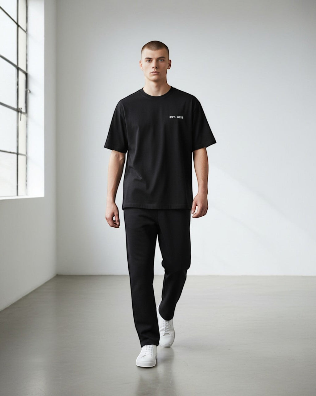 FALLR wear black 100% cotton oversized t-shirt with subtle "EST. 2026" graphic, worn by a male model in a studio setting.