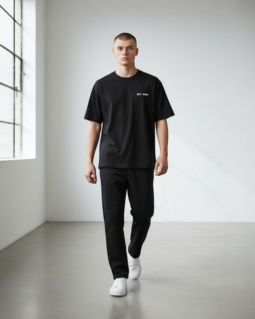 FALLR wear black 100% cotton oversized t-shirt with subtle "EST. 2026" graphic, worn by a male model in a studio setting.