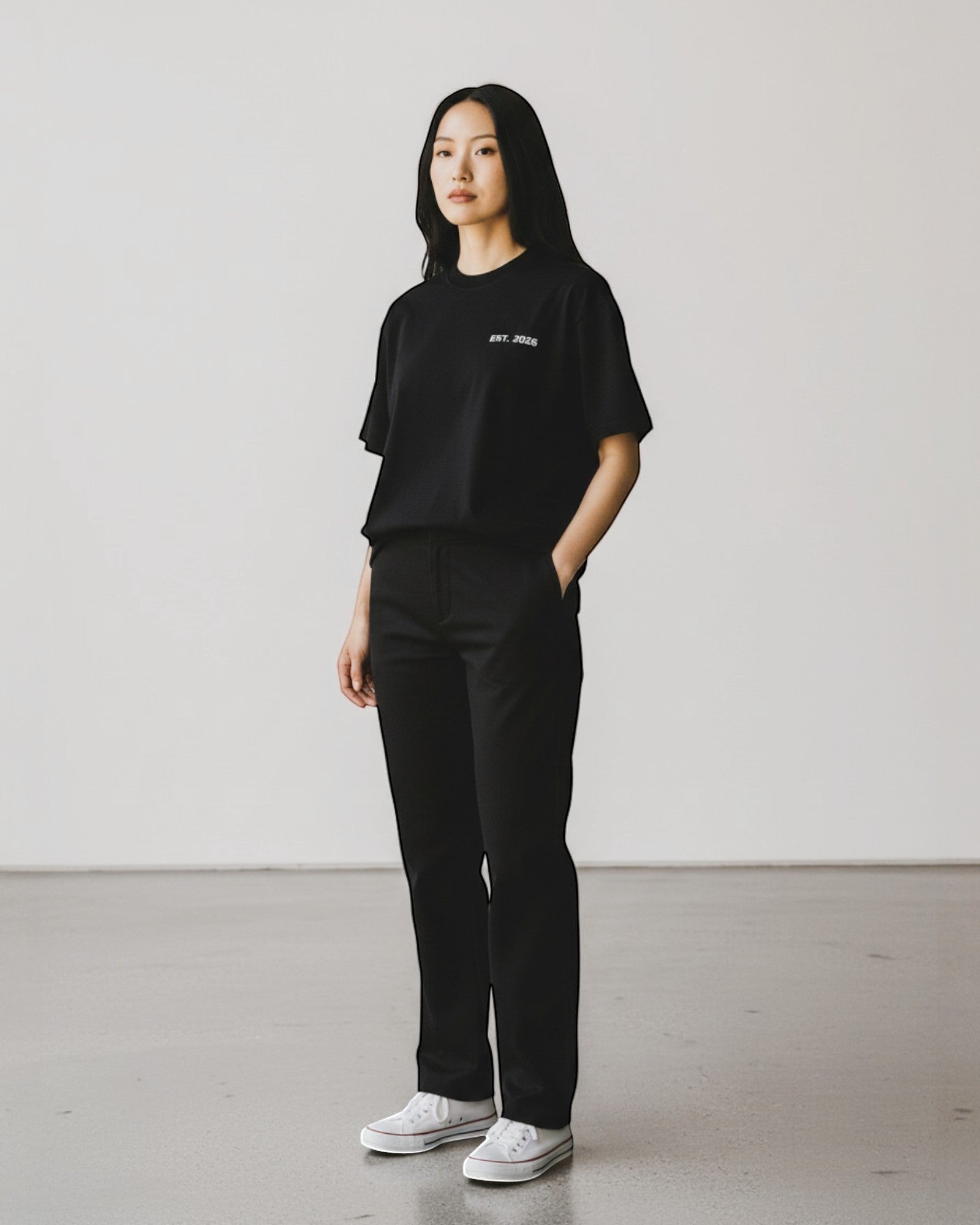 FALLR wear black 100% cotton oversized t-shirt with subtle "EST. 2026" graphic on chest, worn by a woman.