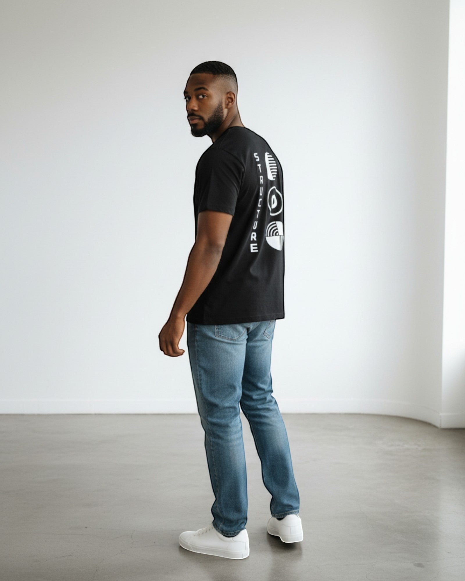 FALLR wear black 100% cotton oversized tee with minimalist white graphic print on back. Model wears jeans and white sneakers.