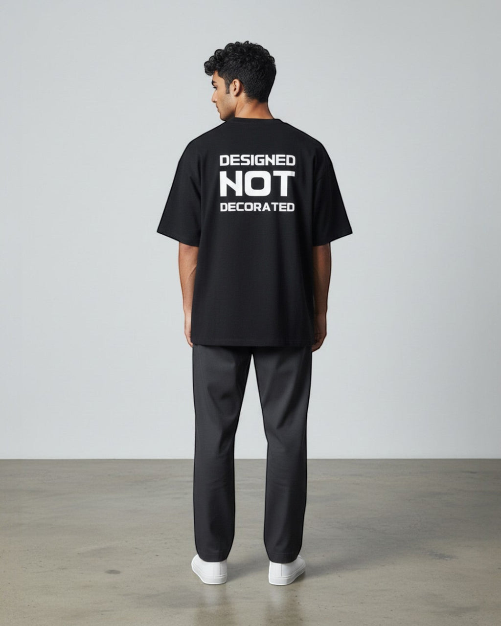 FALLR wear black 100% cotton unisex oversized t-shirt with white 'DESIGNED NOT DECORATED' graphic print on back.