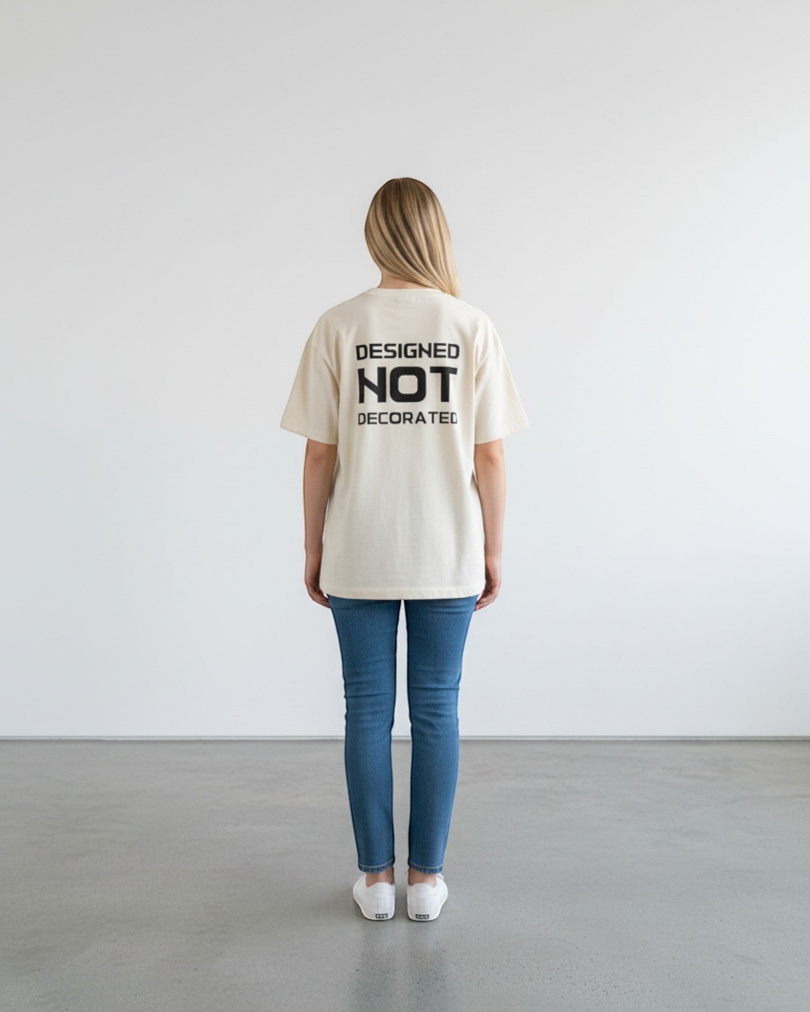 FALLR wear cream 100% cotton unisex oversized t-shirt with black 'DESIGNED NOT DECORATED' graphic on back.