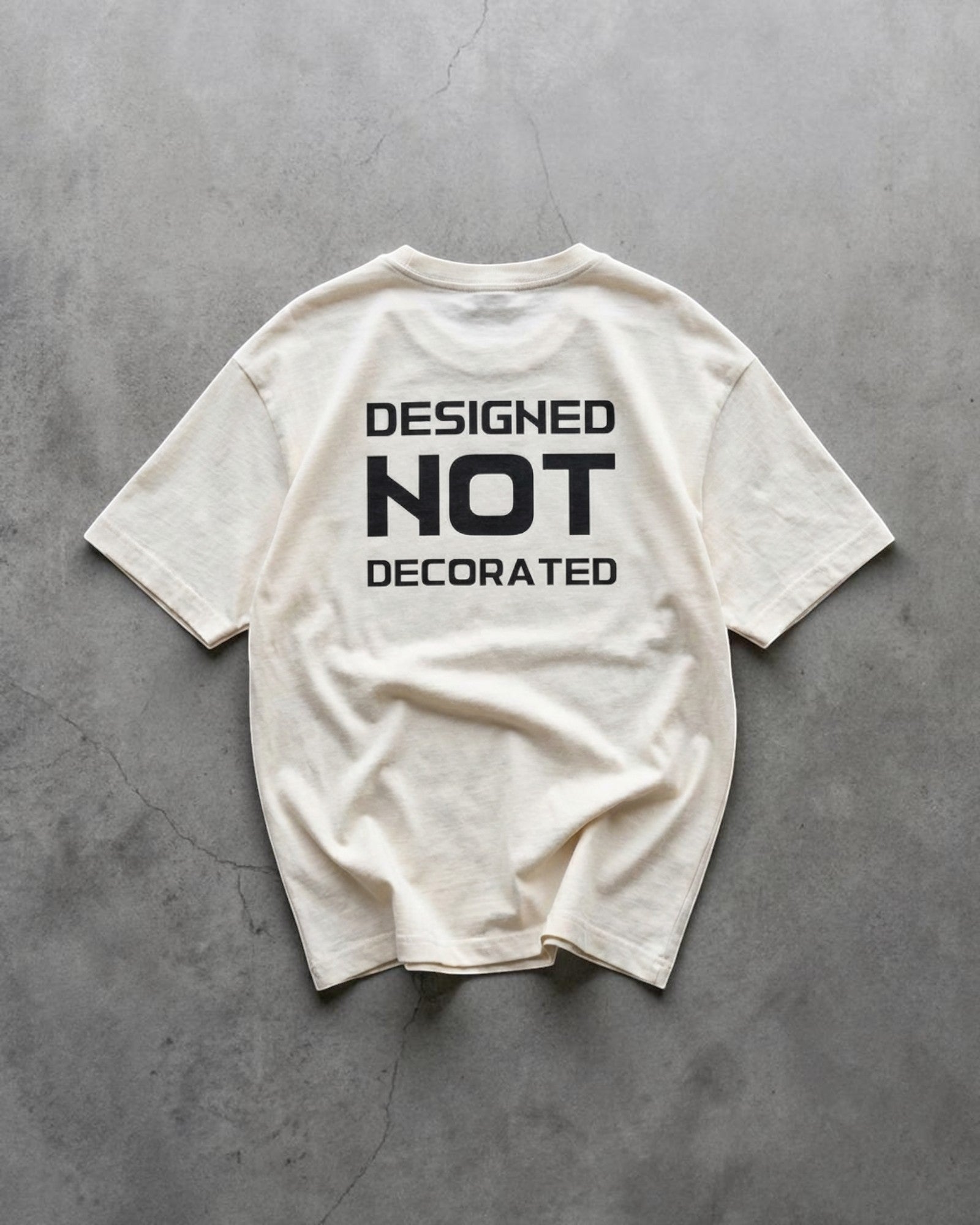 FALLR wear cream 100% cotton unisex oversized t-shirt with black 'DESIGNED NOT DECORATED' graphic print on back.