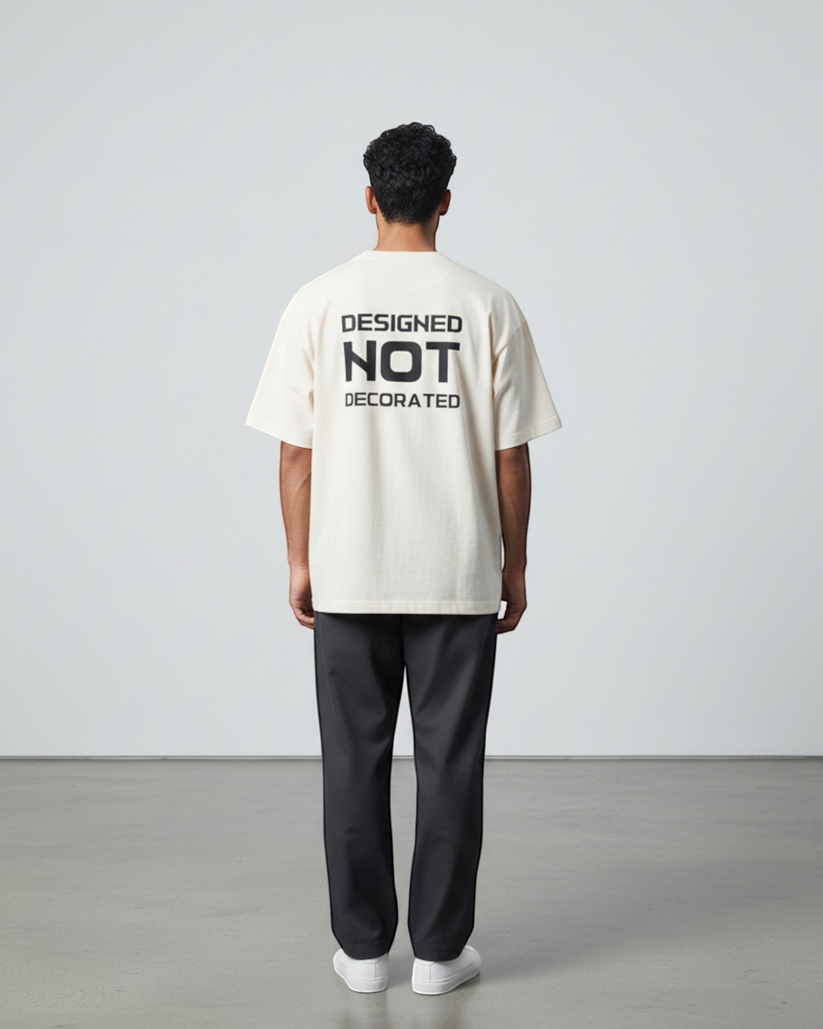 FALLR wear cream 100% cotton unisex oversized t-shirt with black 'DESIGNED NOT DECORATED' graphic print on back.