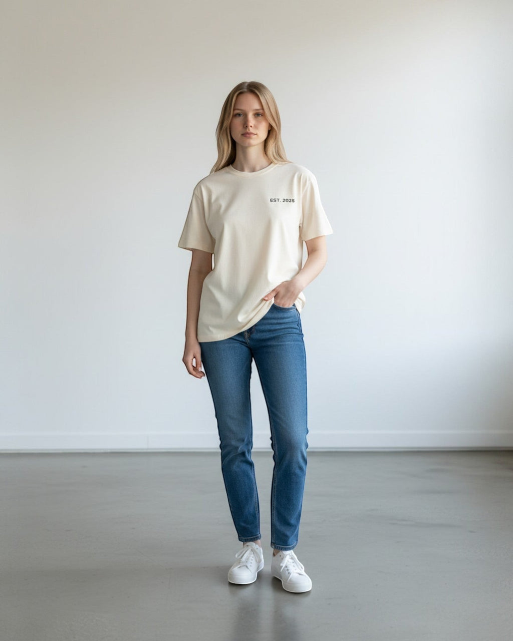 FALLR wear cream 100% cotton oversized t-shirt with "EST. 2026" graphic print on chest, worn by a woman with blue jeans.