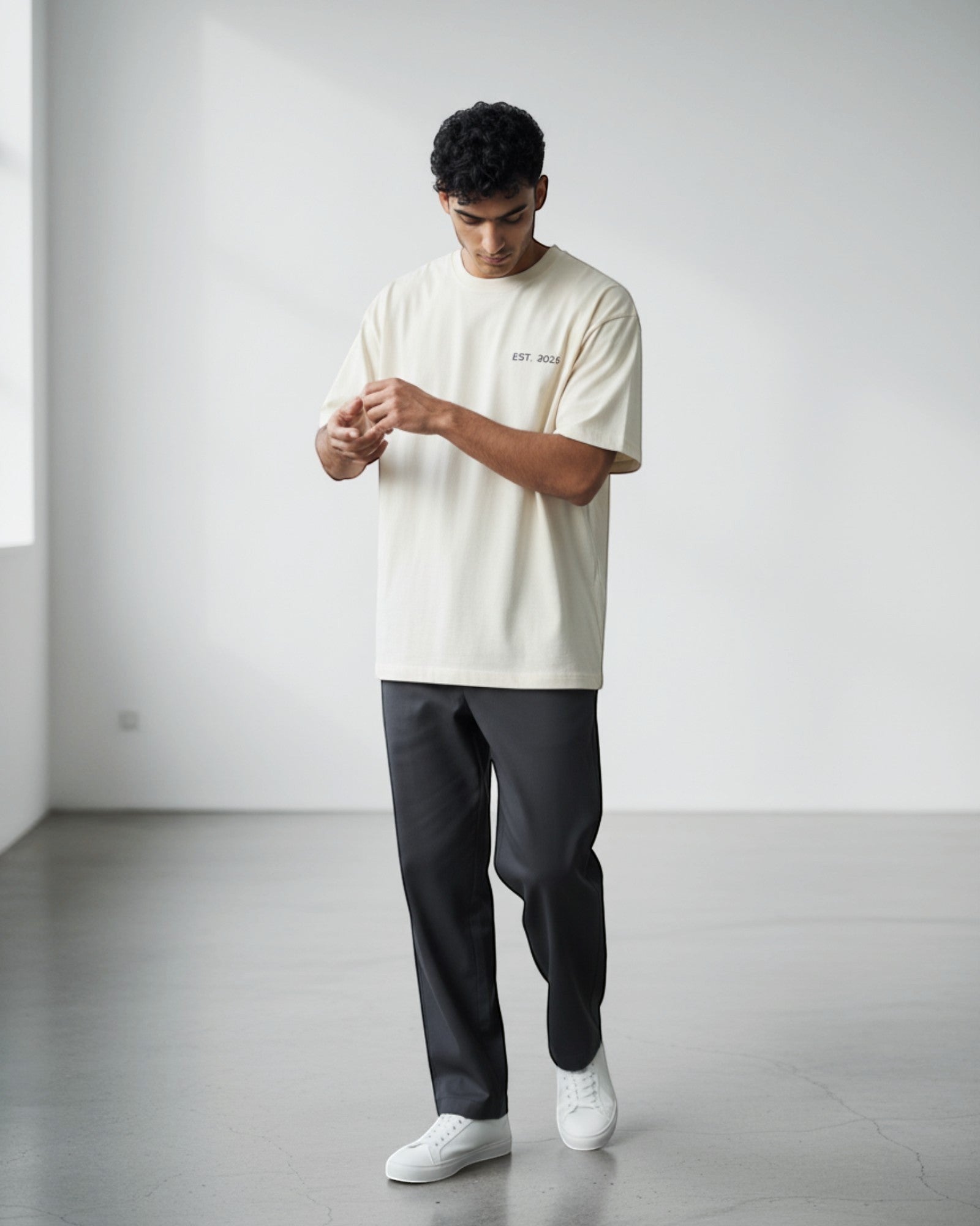 FALLR wear cream 100% cotton oversized unisex t-shirt with minimal graphic print and dark grey trousers.