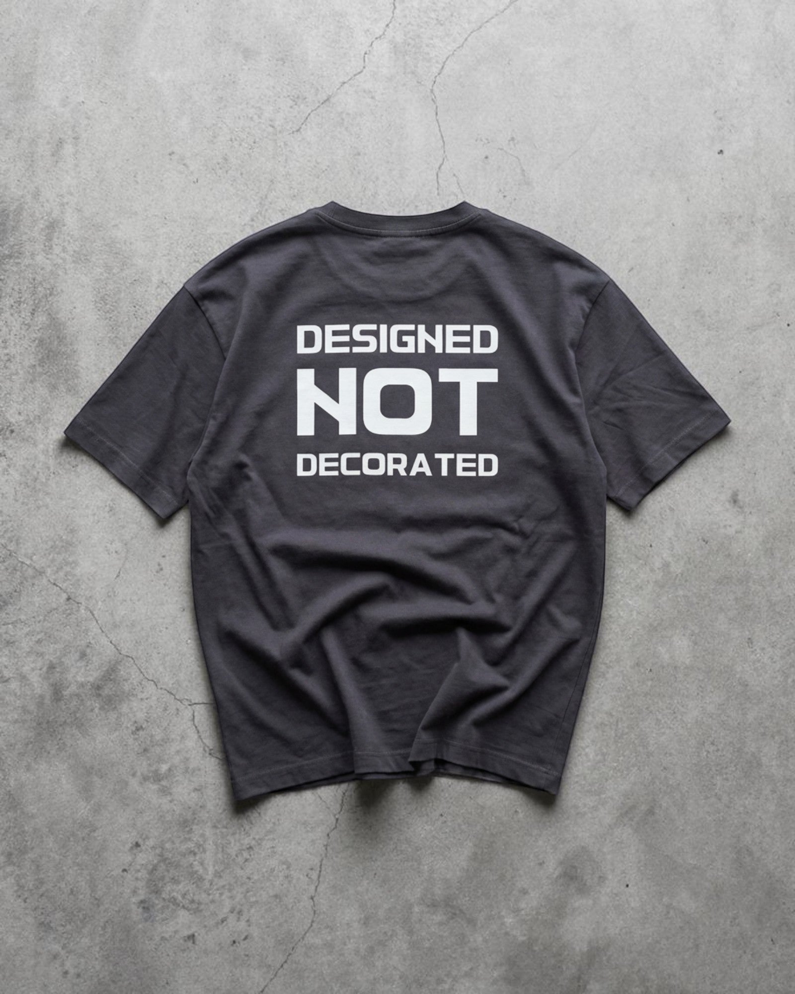 FALLR wear dark grey 100% cotton unisex oversized t-shirt with white 'DESIGNED NOT DECORATED' graphic print on back.