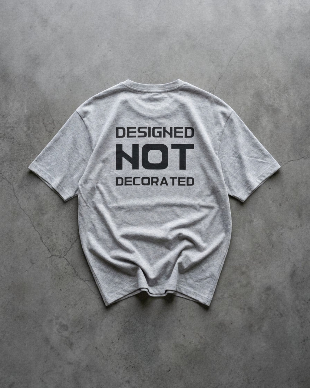 FALLR wear grey 100% cotton unisex oversized t-shirt with black 'DESIGNED NOT DECORATED' graphic print on back.