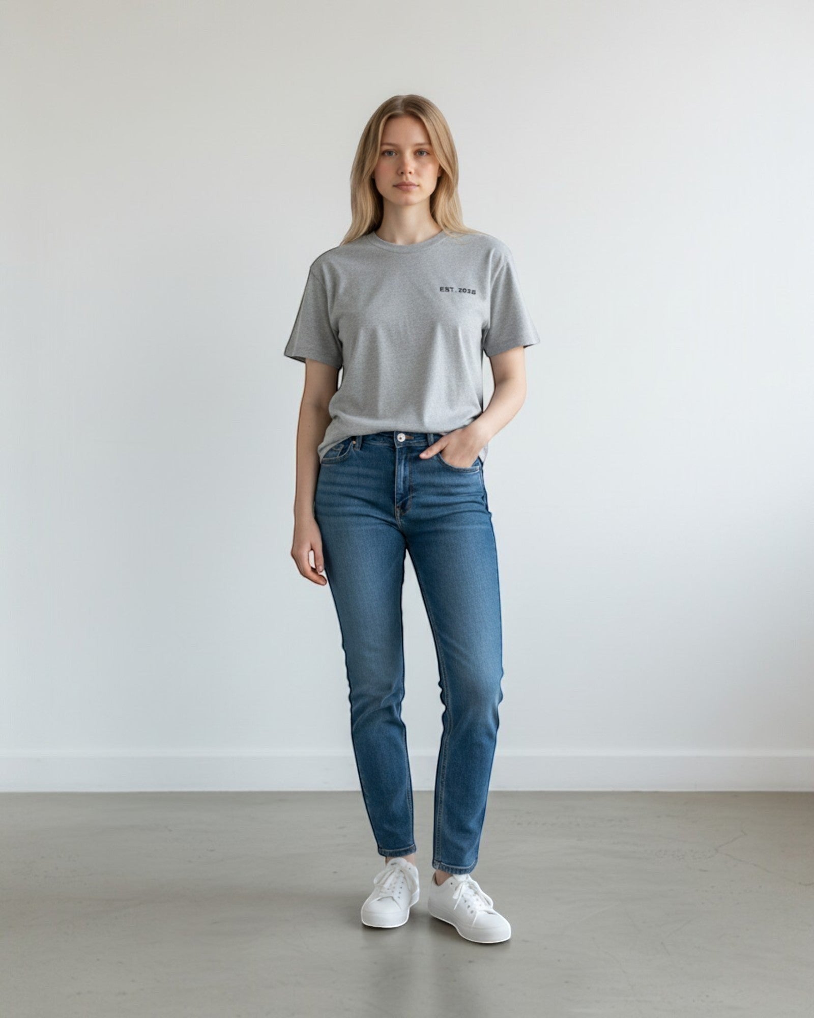 FALLR wear grey 100% cotton oversized t-shirt with subtle "EST. 2020" graphic on chest, worn by a woman with blue jeans and white sneakers.