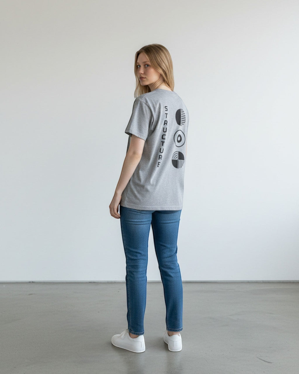 FALLR wear grey 100% cotton oversized t-shirt with black graphic print on back. Model is wearing jeans and white sneakers.