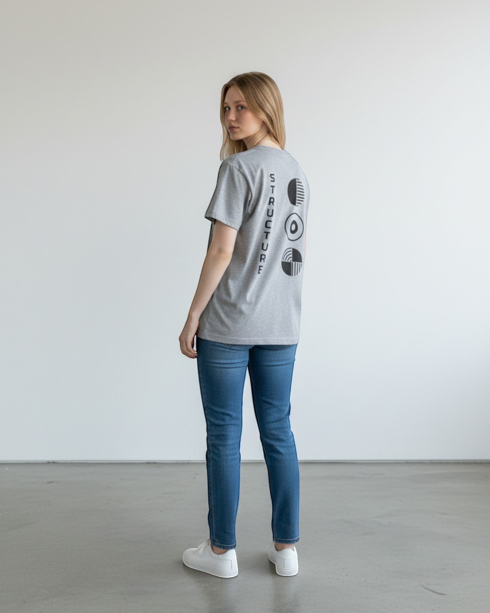 FALLR wear grey 100% cotton oversized t-shirt with black graphic print on back. Model is wearing jeans and white sneakers.