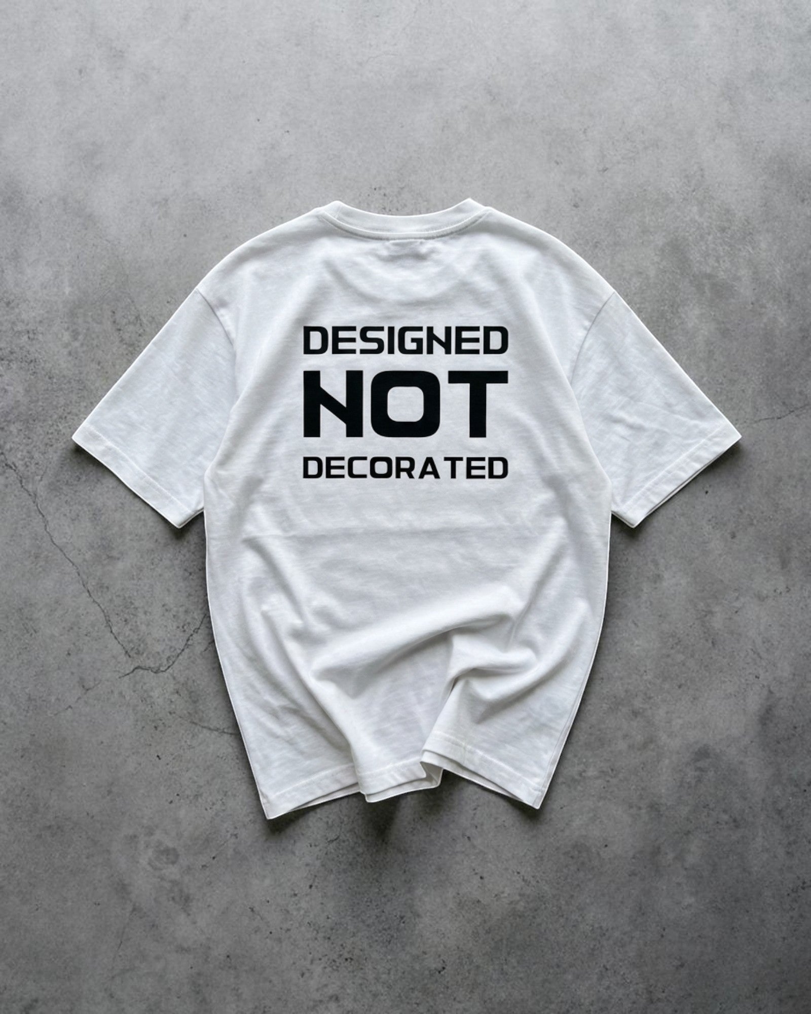 FALLR wear white 100% cotton unisex oversized t-shirt with black 'DESIGNED NOT DECORATED' graphic print on back.
