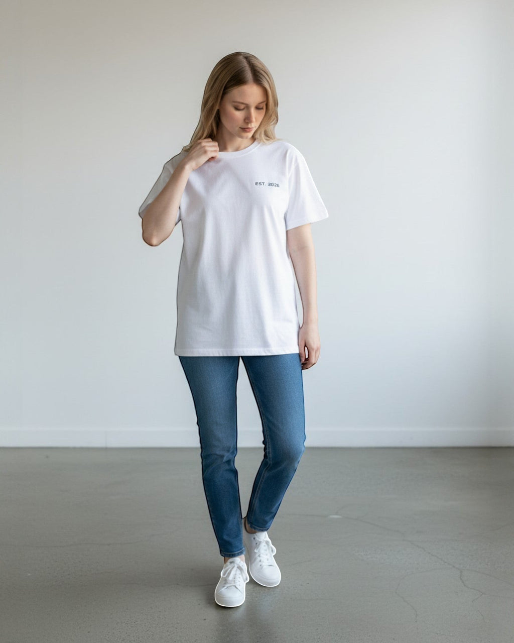 FALLR wear white 100% cotton oversized t-shirt with minimal graphic print, worn by a woman with blue jeans and white sneakers.