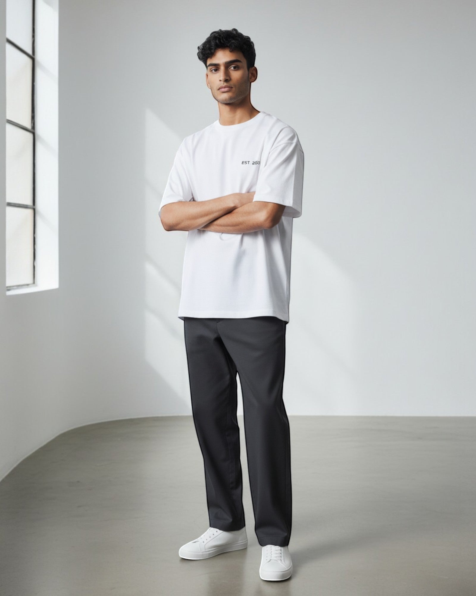FALLR wear white 100% cotton oversized t-shirt with subtle chest graphic, worn by a man with arms crossed.