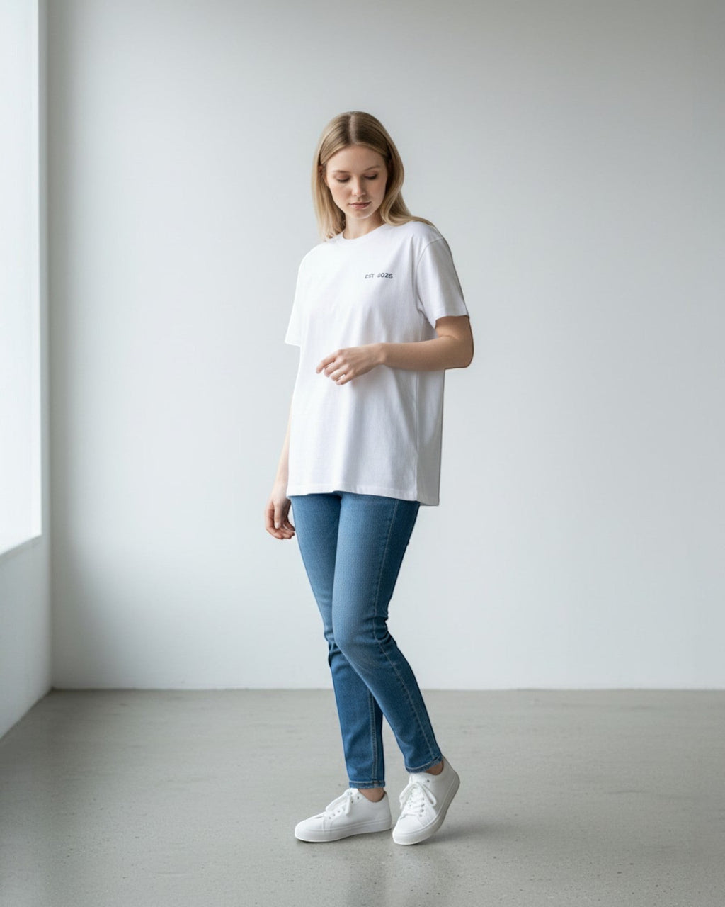 FALLR wear white 100% cotton oversized t-shirt with minimalist graphic print and relaxed fit, worn by a woman with blue jeans and white sneakers.