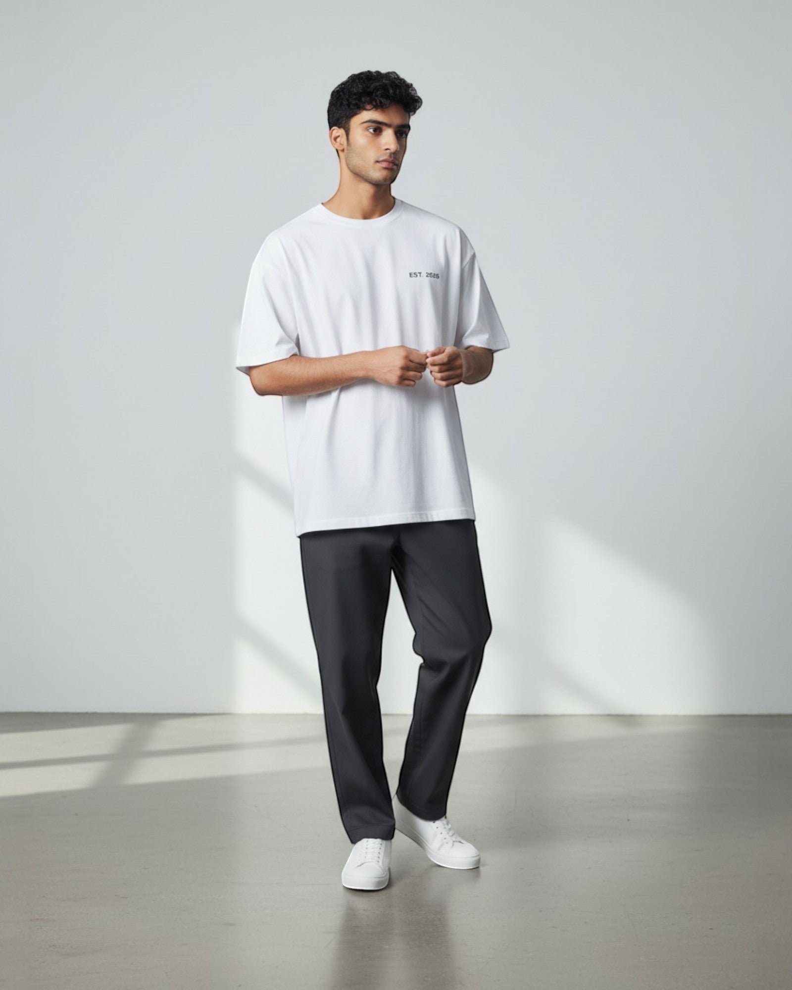 FALLR wear white 100% cotton oversized t-shirt with minimal graphic print and relaxed fit, paired with charcoal grey trousers.